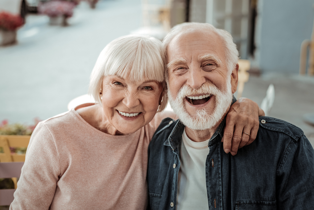 couple smiling indoors, representing healthy aging and dental wellness