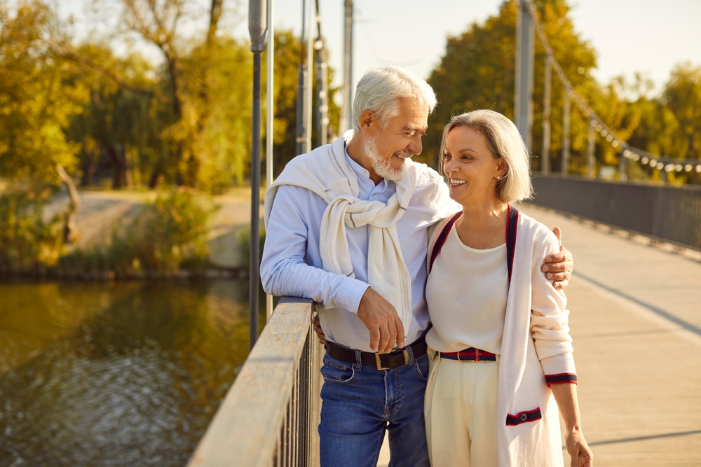 Smiling senior couple walking arm in arm on a footbridge