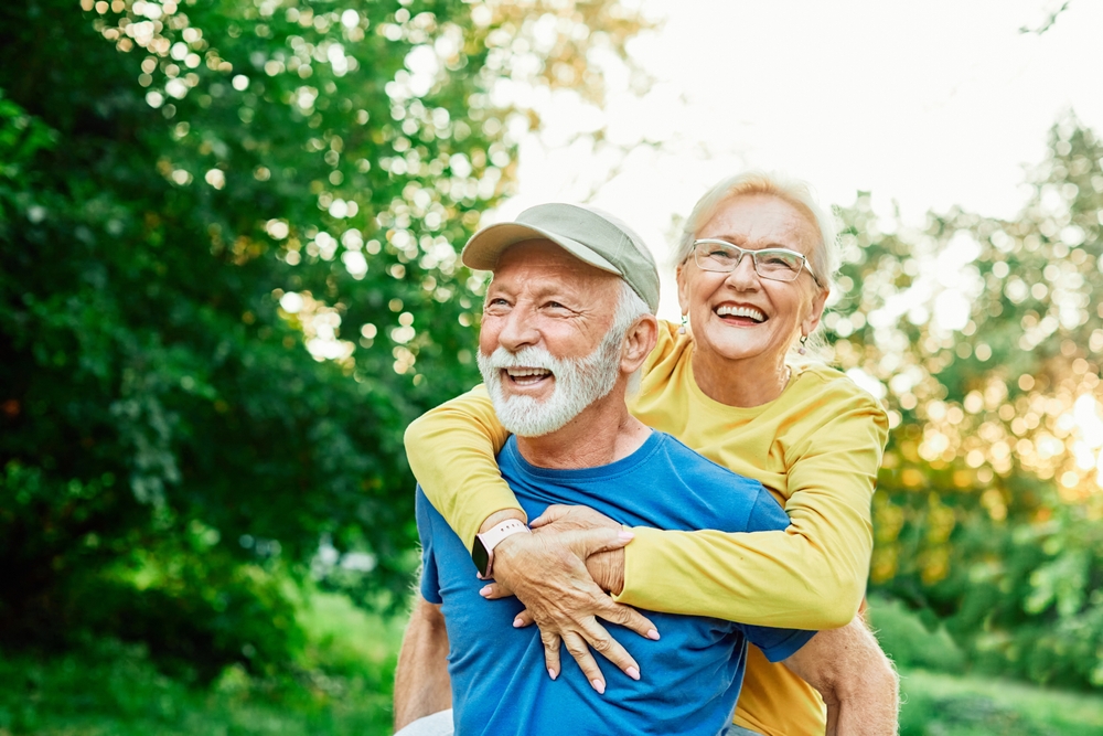 Happy couple walking outdoors, representing confident smiles and healthy dental results with Sedation Dentistry