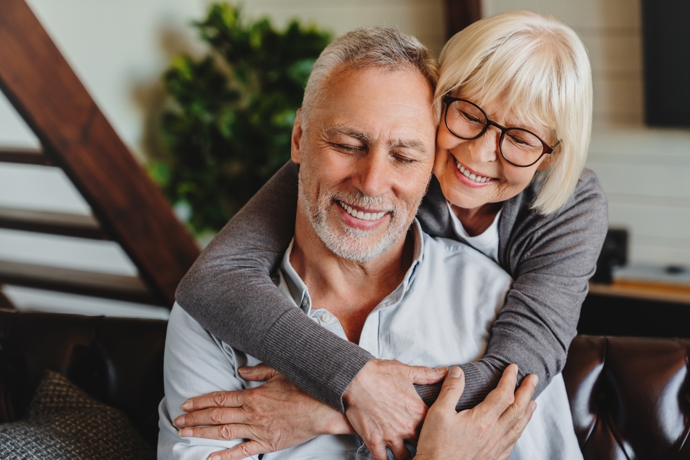 Happy couple smiling together at home, representing comfortable and confident dental care results