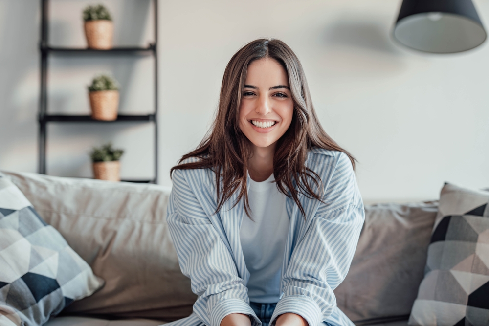 Woman smiling on couch showing results of cosmetic dentistry in Rapid City
