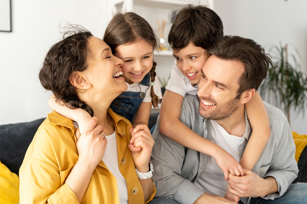 A laughing family hugging together on a couch